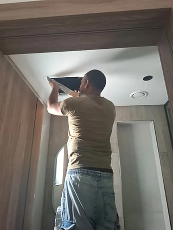 Technician working on a ceiling access panel