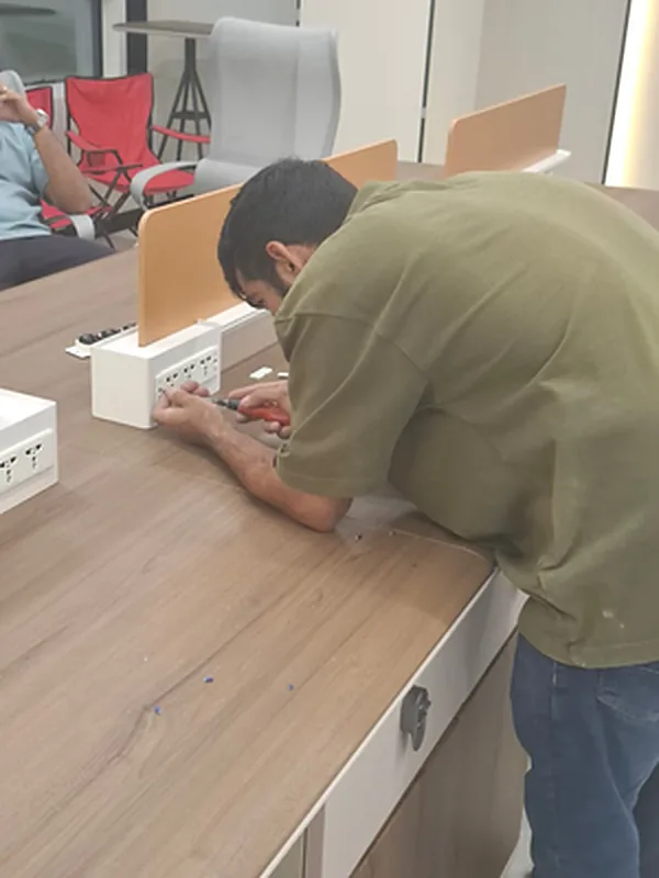 Technician installing power sockets on office workstations