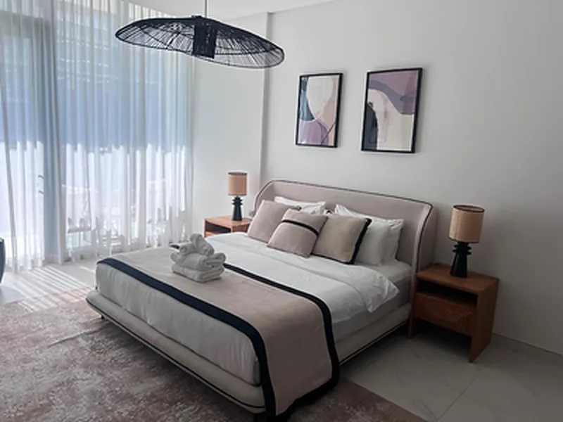 Holiday home bedroom with styled bedding, pendant light and framed art