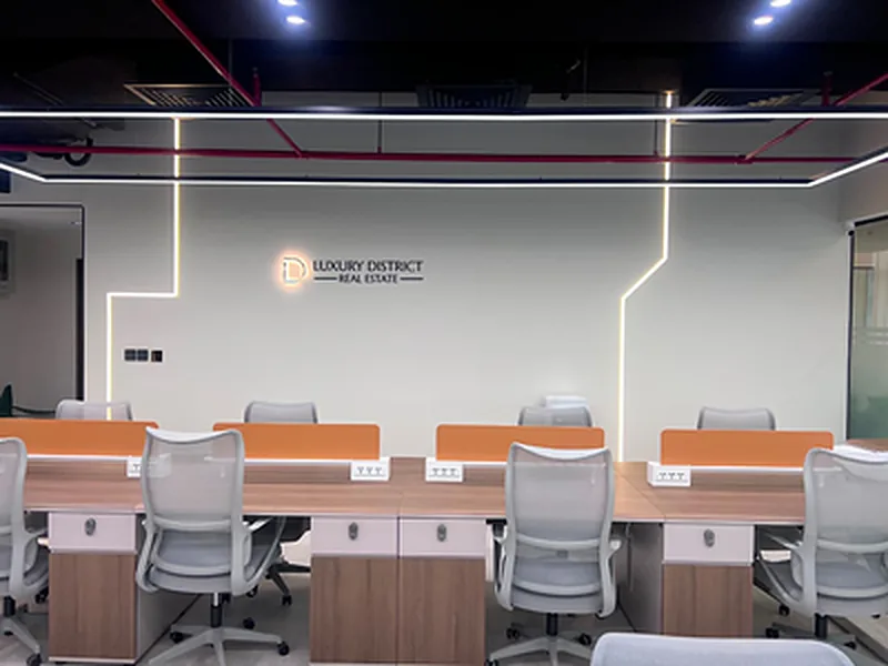 Open-plan office with rows of workstations and linear ceiling lights