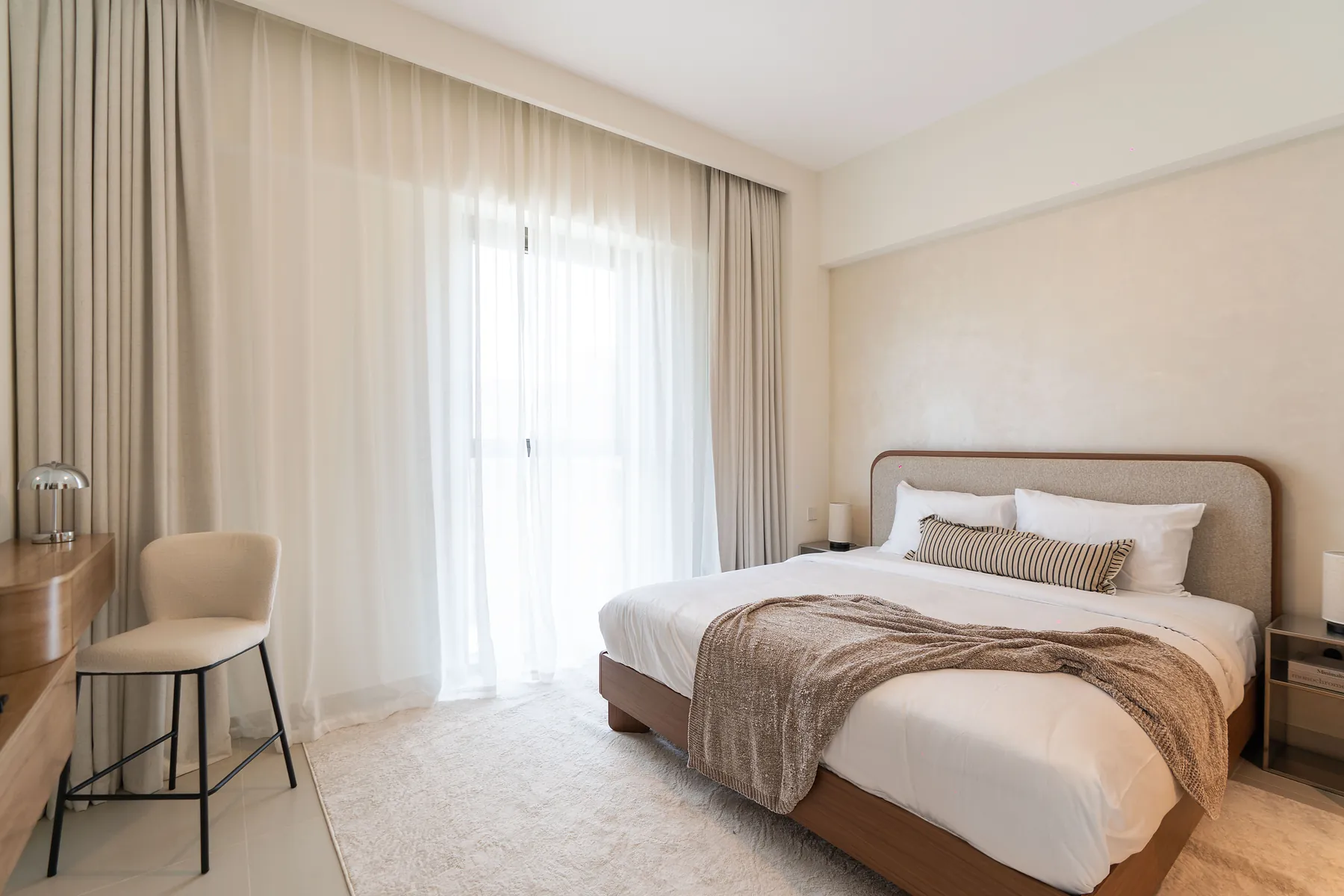 Bedroom with upholstered bed, floating vanity desk and bar stool