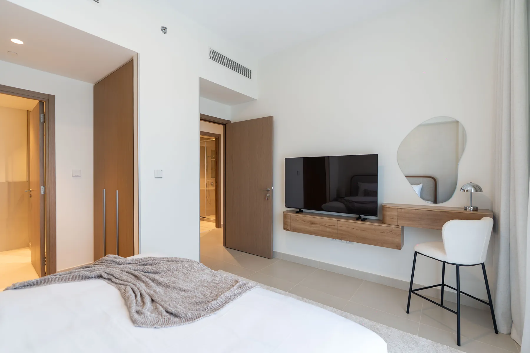Bedroom with wall-mounted TV, floating timber unit and vanity mirror