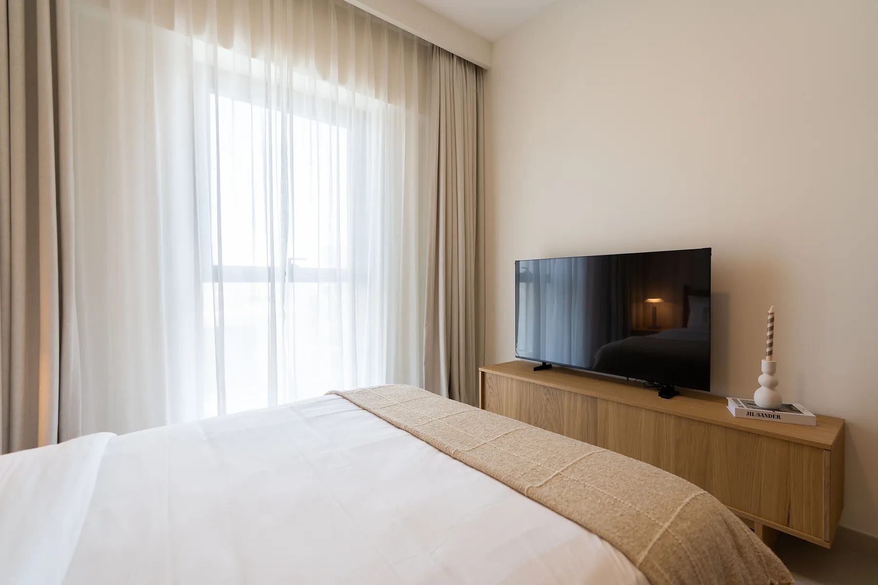 Bedroom with low timber TV console and sheer curtains