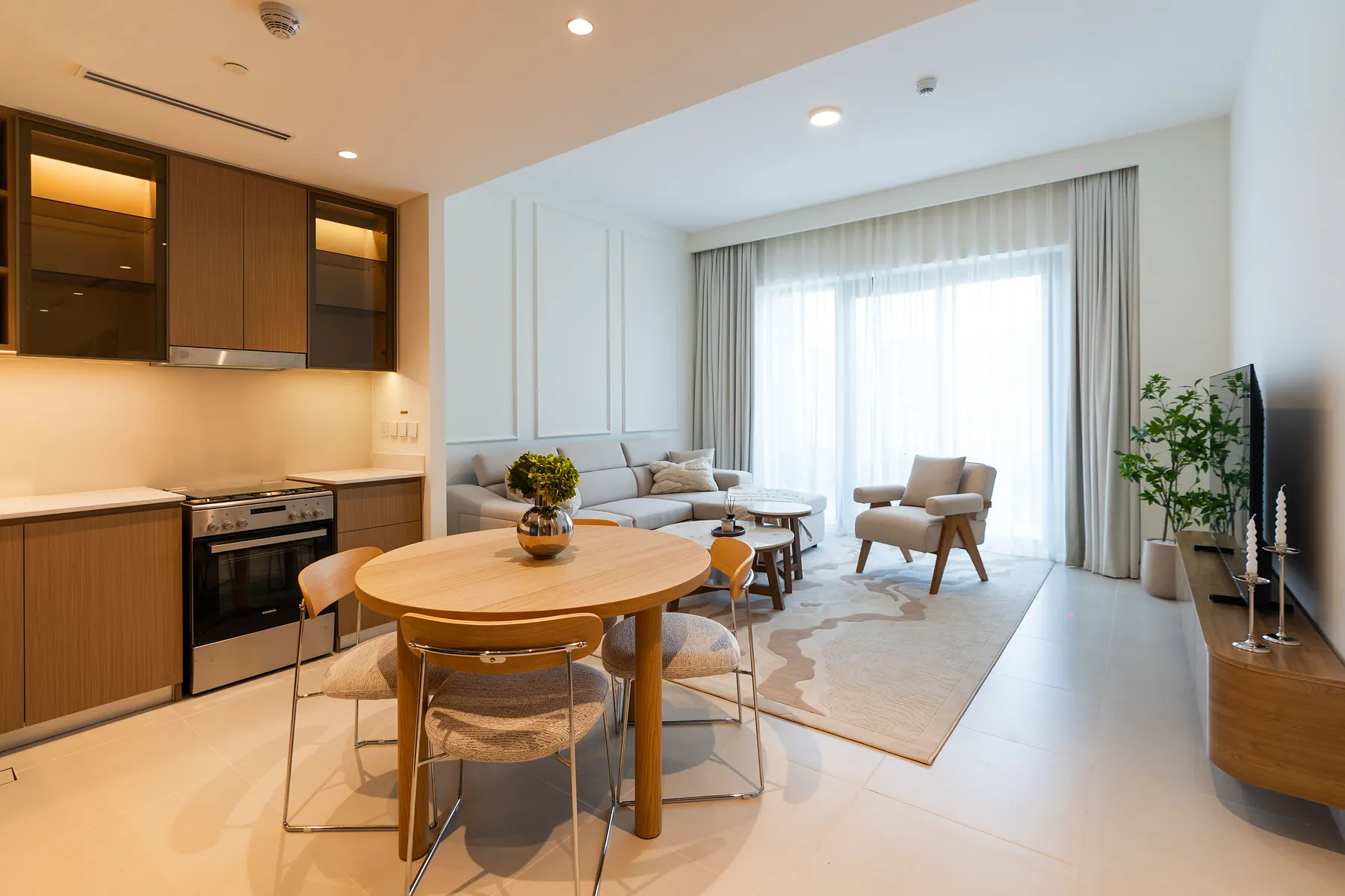 Open-plan kitchen with timber cabinets, round dining table and living area