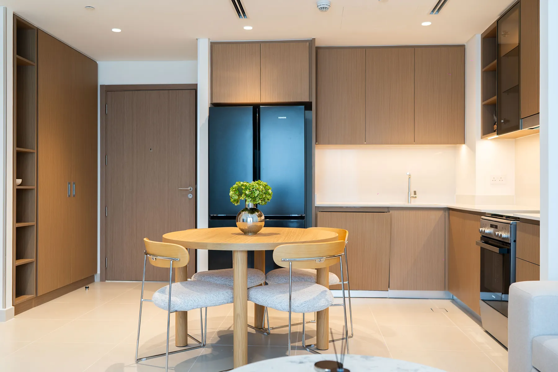 Fitted kitchen with timber cabinetry, black refrigerator and round dining table