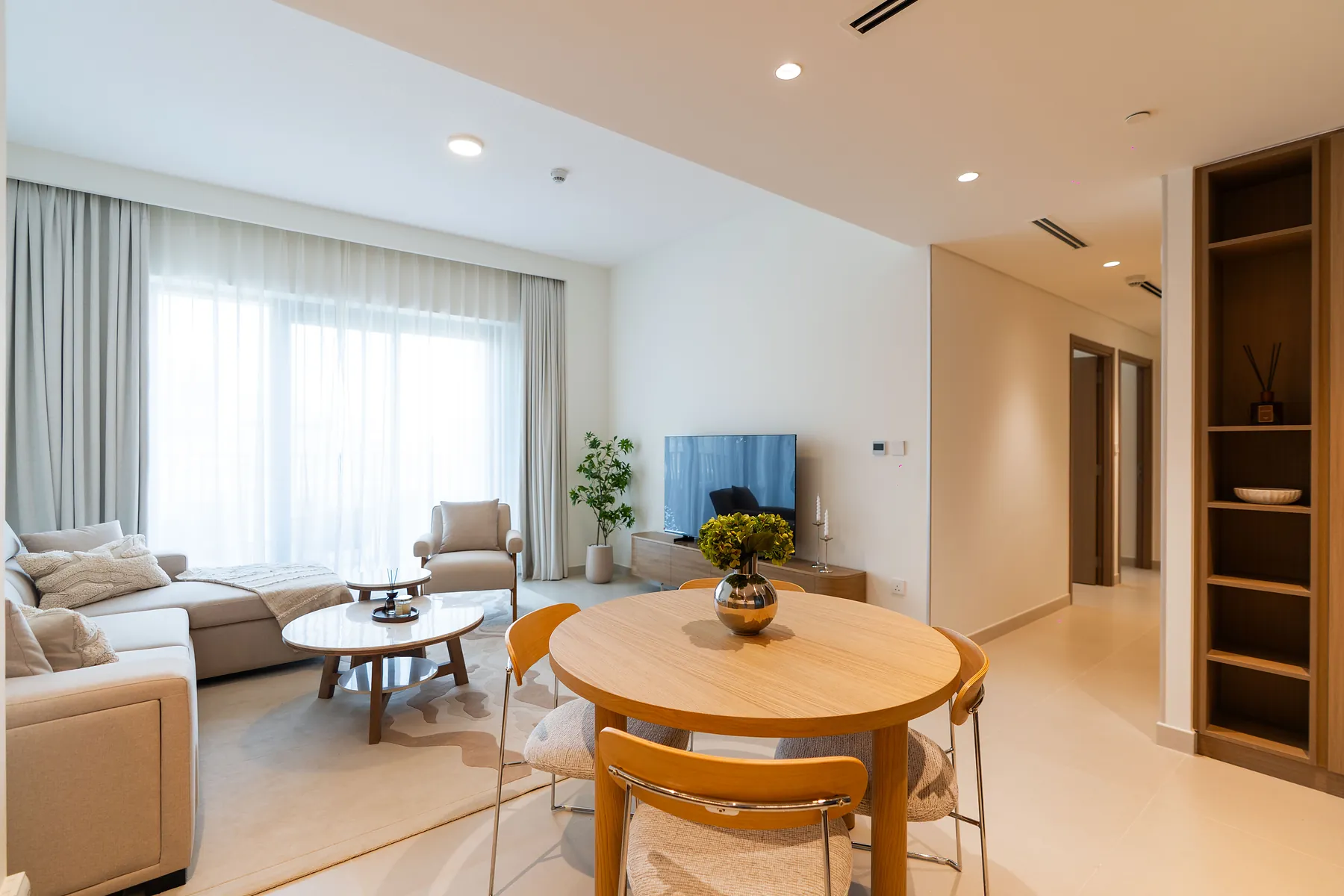 Living and dining area with round timber table, sofa and full-height built-in shelving