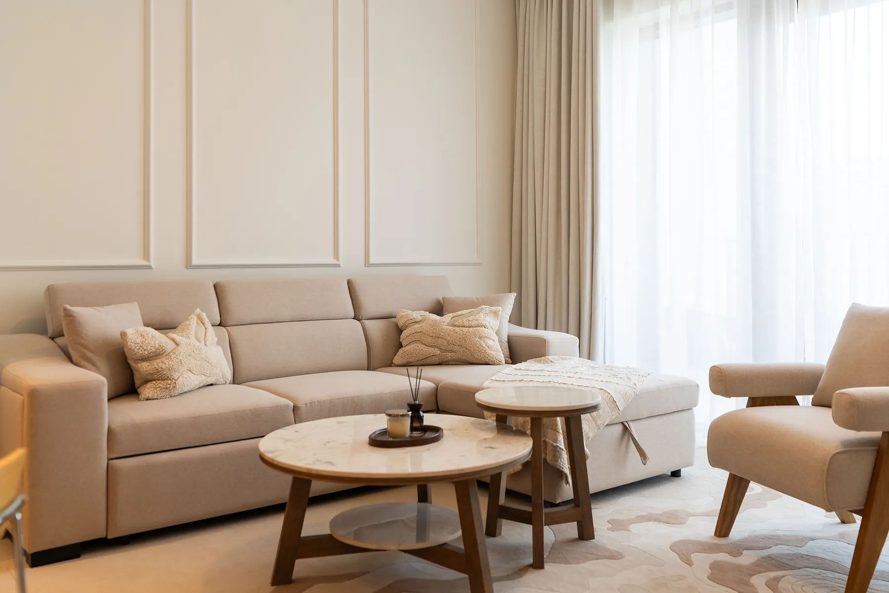 Beige sectional sofa with marble-top coffee tables and panelled wall