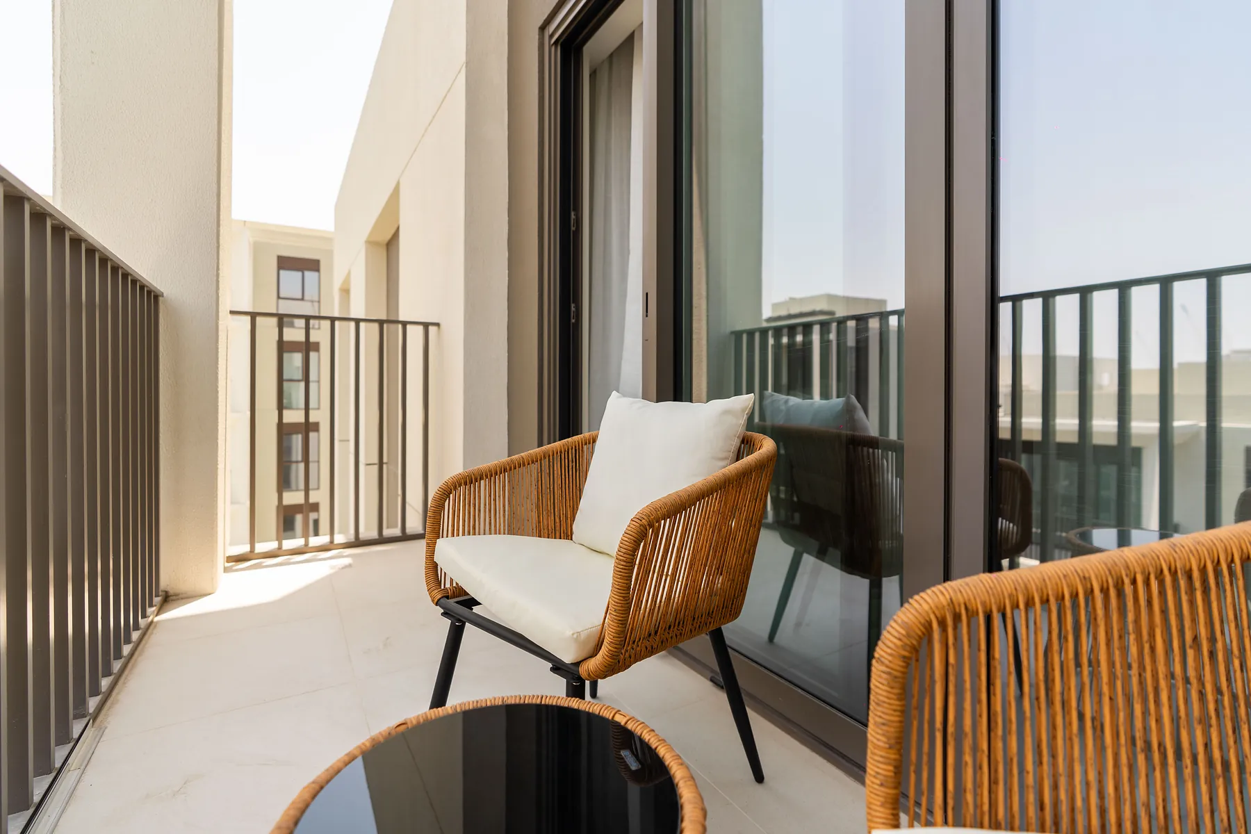 Balcony seating with rattan chairs beside floor-to-ceiling glass doors