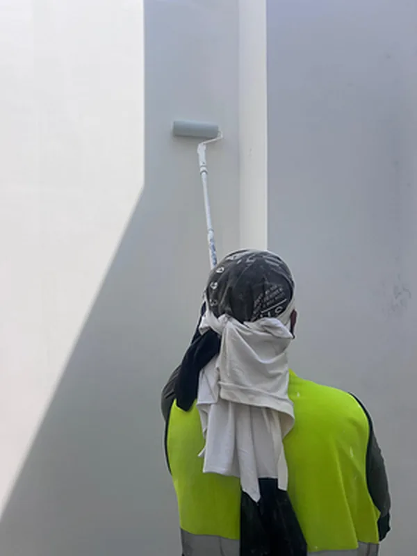 Painter using an extension roller on a tall interior wall
