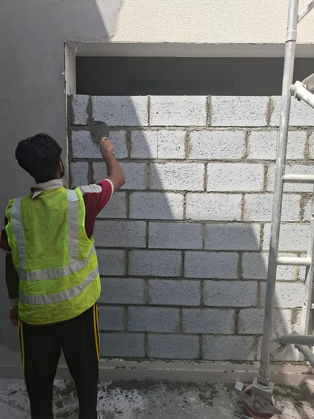 Worker in a high-visibility vest preparing blockwork on site