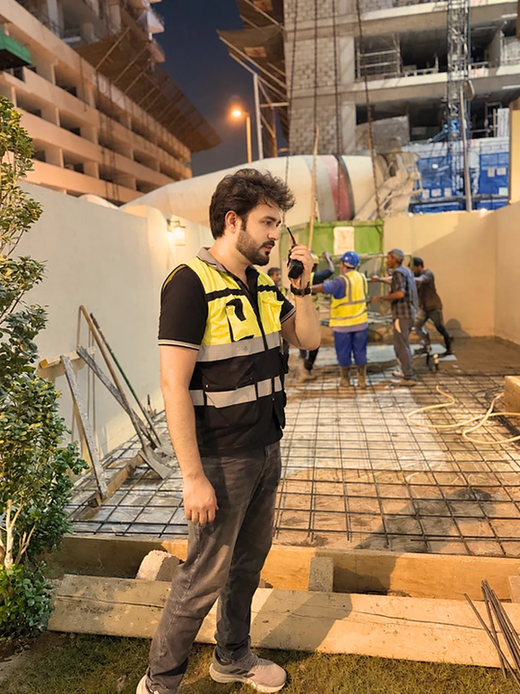 Site supervisor with radio overseeing a concrete slab pour at night